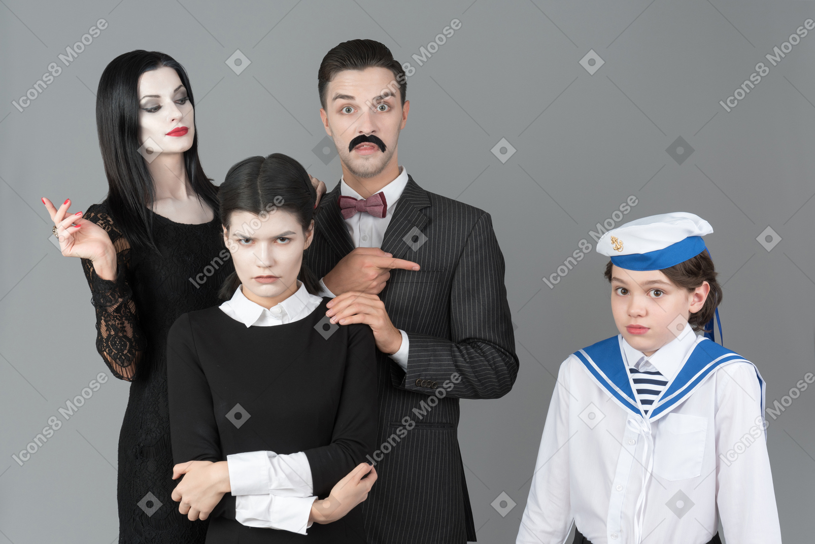 Addams family members pointing at confused boy in sailor's uniform