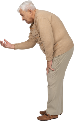 一位穿着休闲服的老人伸出手臂站立的侧视图