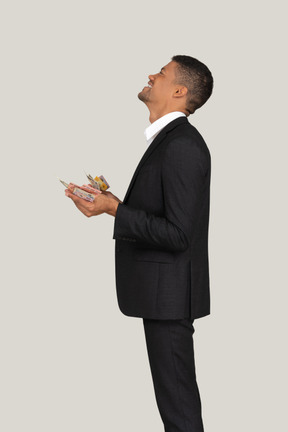 Vista laterale di un giovane in abito nero che tiene banconote