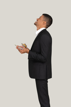 Side view of a young man in black suit holding banknotes