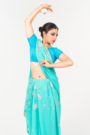 Joven mujer india en sari azul de pie en posición de baile