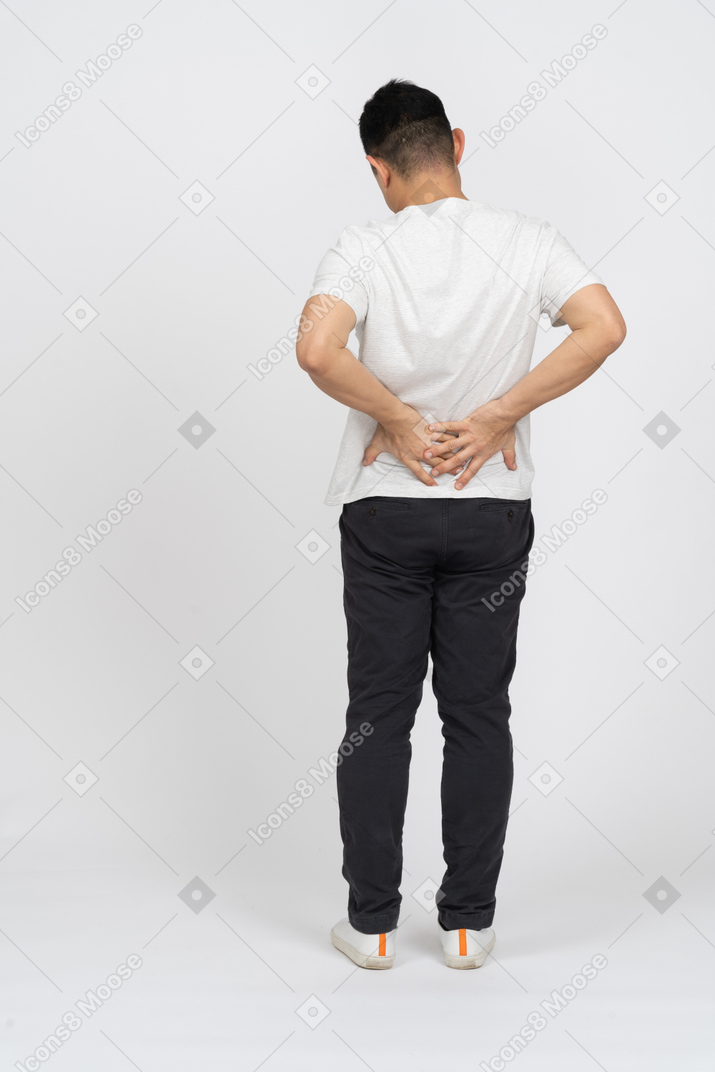 背中の痛みに苦しんでいるカジュアルな服を着た男の背面図