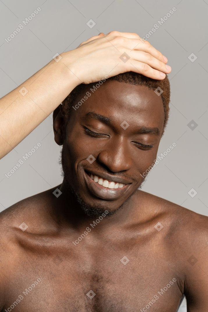 White hand touching hair of a black young man