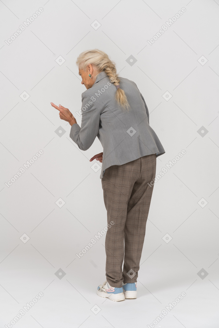 Rear view of an old lady in suit showing a warning sign