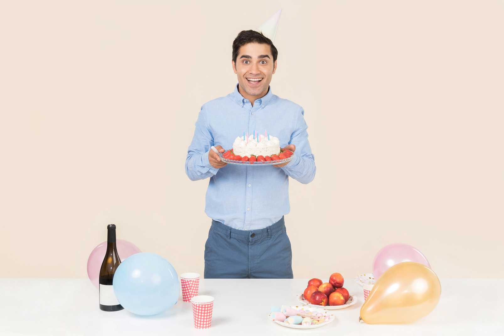 Young man standing at the birthday table and holding cake