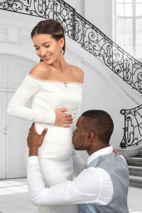 A man kissing a pregnant woman's stomach