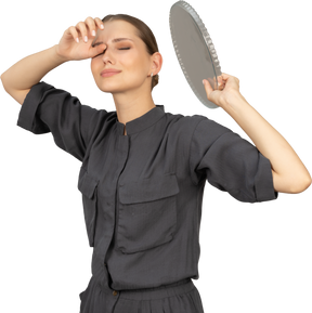 Three-quarter view of a young woman in a jumpsuit holding glass plate