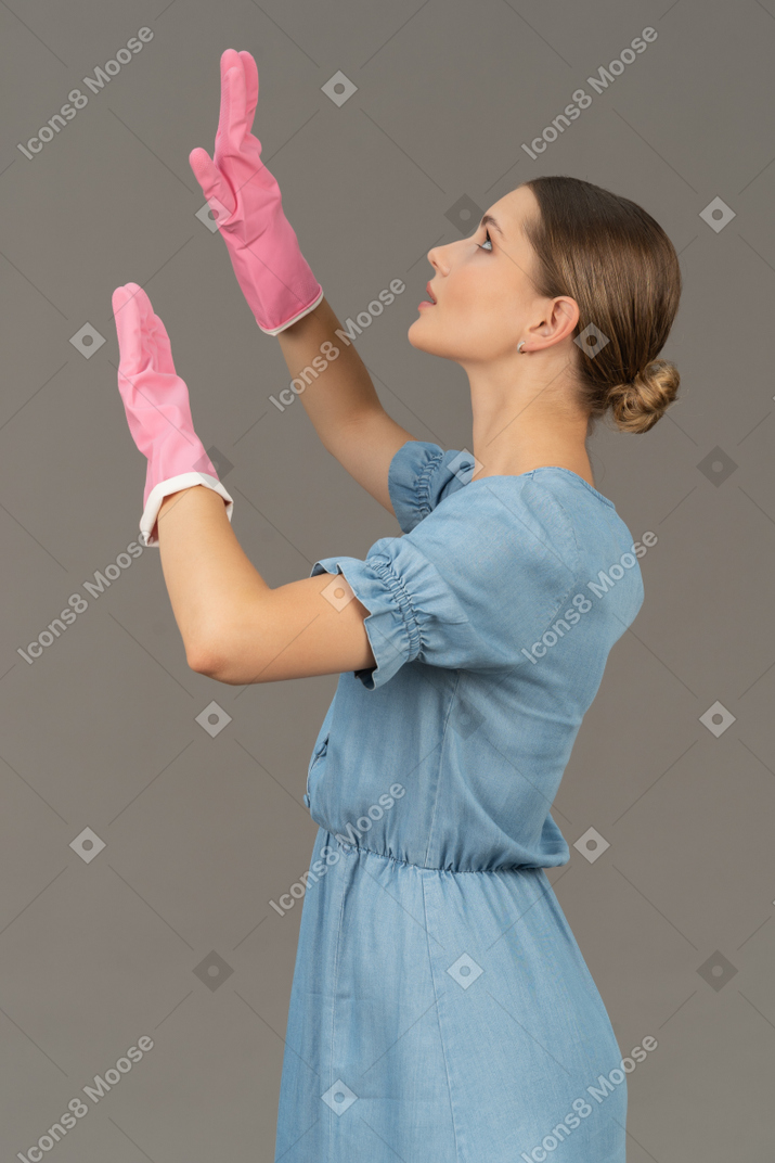 Side view of a young woman looking up while wearing latex gloves