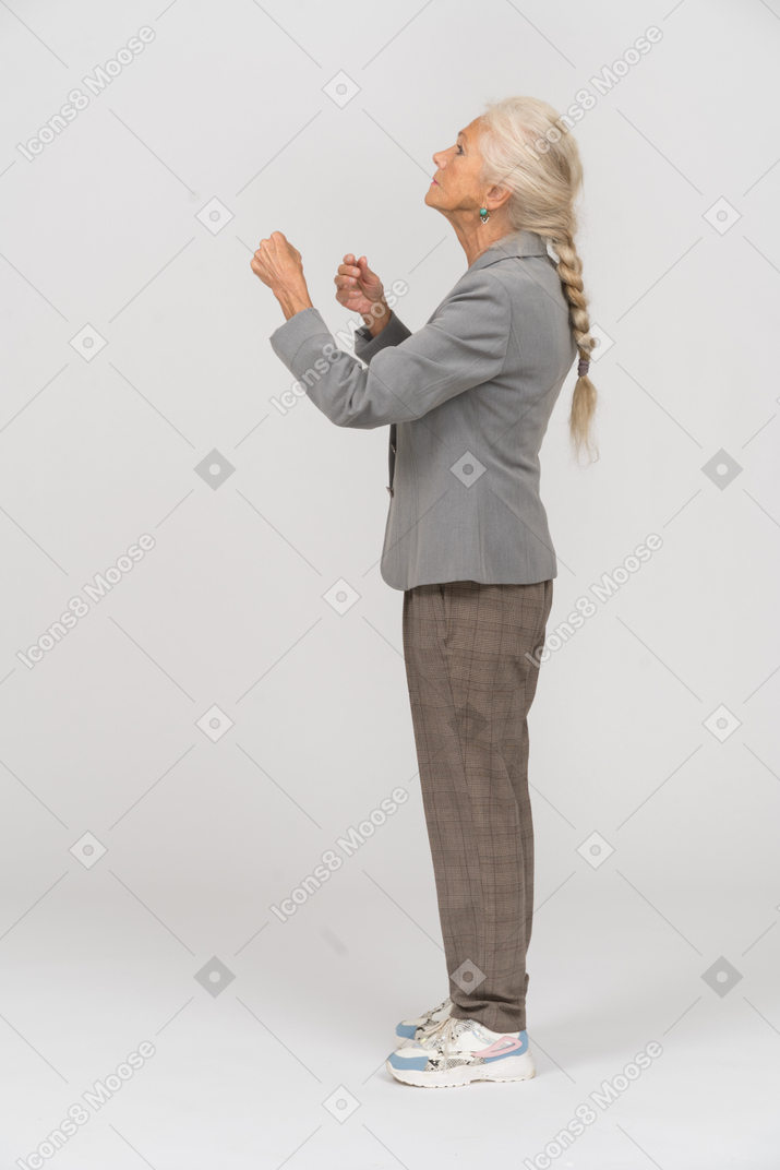 Side view of an old lady in suit holds imaginary steering wheel
