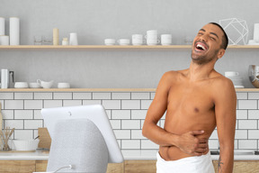 A shirtless man standing in front of a computer