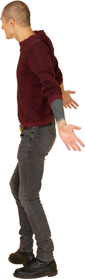 Vista lateral de un joven sorprendido en jersey rojo extendiendo sus manos