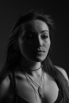 Noir de cabeza a hombro retrato de una mujer joven con arte facial mirando a un lado
