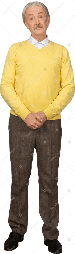Front view of a confused old man holding hands together and wearing yellow pullover