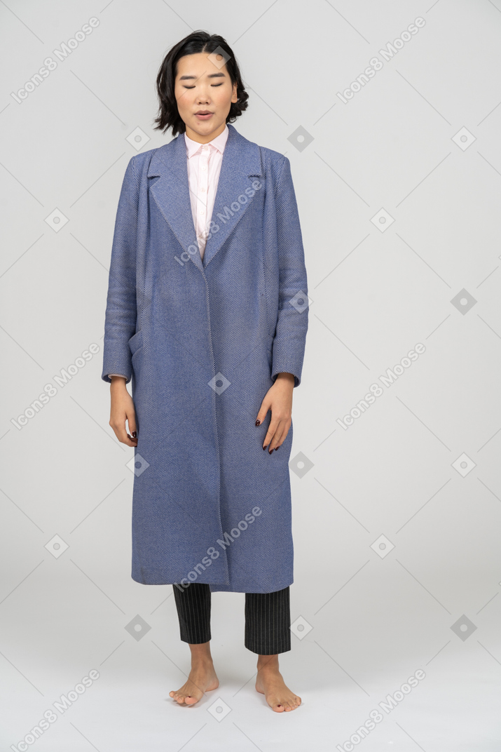 Mulher de casaco em pé com os olhos fechados
