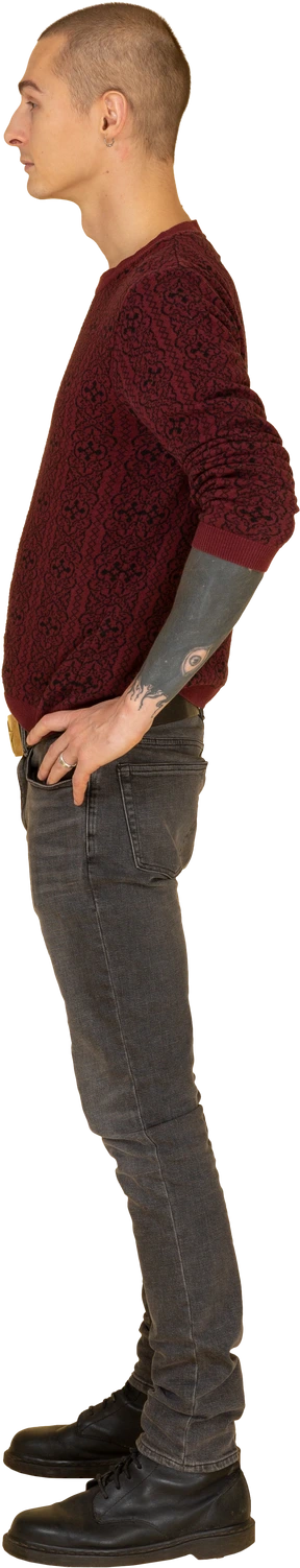 Side view of a young man in pullover putting hands on hips