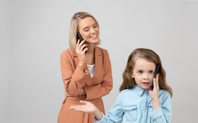 女儿在电话上交谈作为她的妈妈