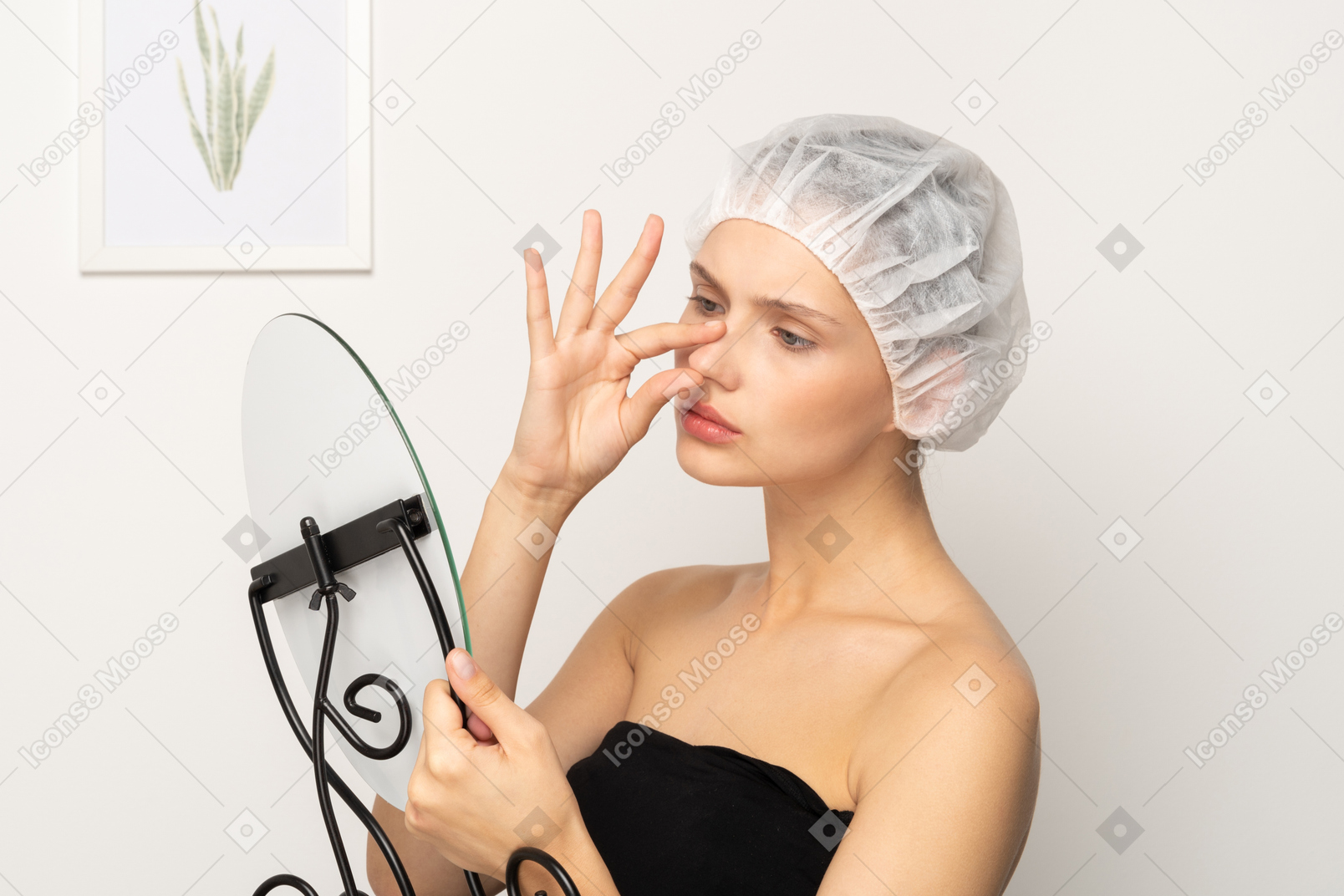 Unhappy young woman looking in the mirror and touching her nose