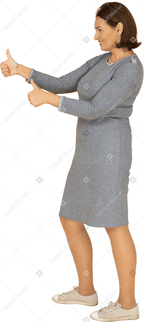 Side view of a woman in grey dress showing thumbs up