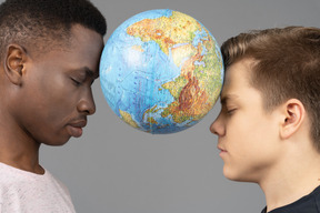 Two young men holding the earth globe between their foreheads