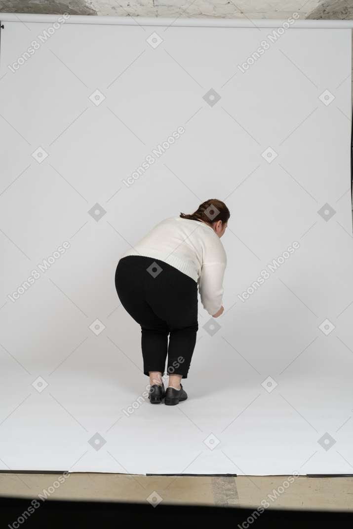 Rear view of a plus size woman in casual clothes bending down