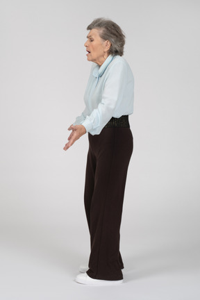 Vista lateral de una anciana encogiéndose de hombros expresivamente