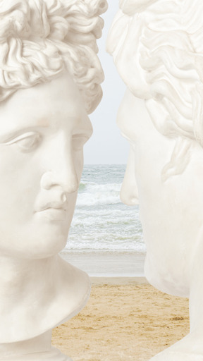 White statues facing each other on sandy beach