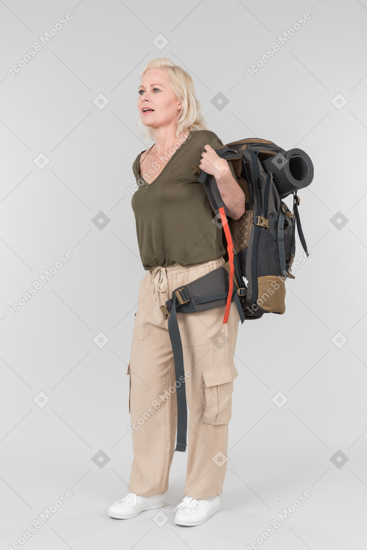 Mature female tourist putting off heavy backpack she was carrying