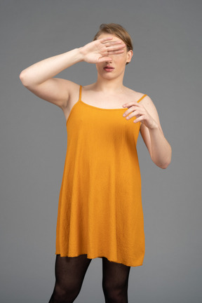Genderqueer person covering face with back of hand