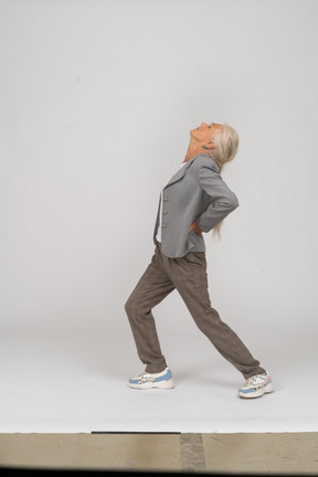 Side view of an old lady in suit doing yoga