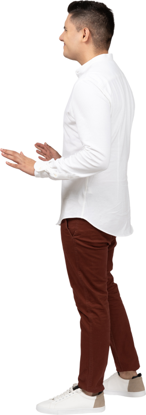 Vista laterale di un giovane uomo latino arricciando il naso con disgusto e alzando leggermente le mani nel gesto discendente