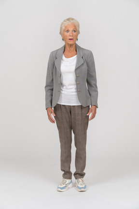 Front view of a shocked old woman in suit staring at something