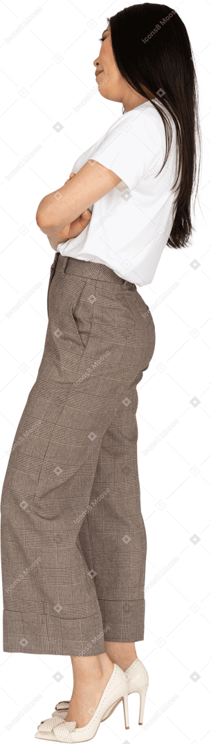 Vista lateral de uma jovem entediada de calça e camiseta cruzando as mãos e inclinando a cabeça