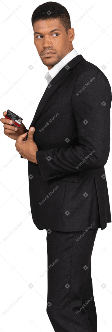 Vue latérale d'un jeune homme en costume noir tenant une carte bancaire
