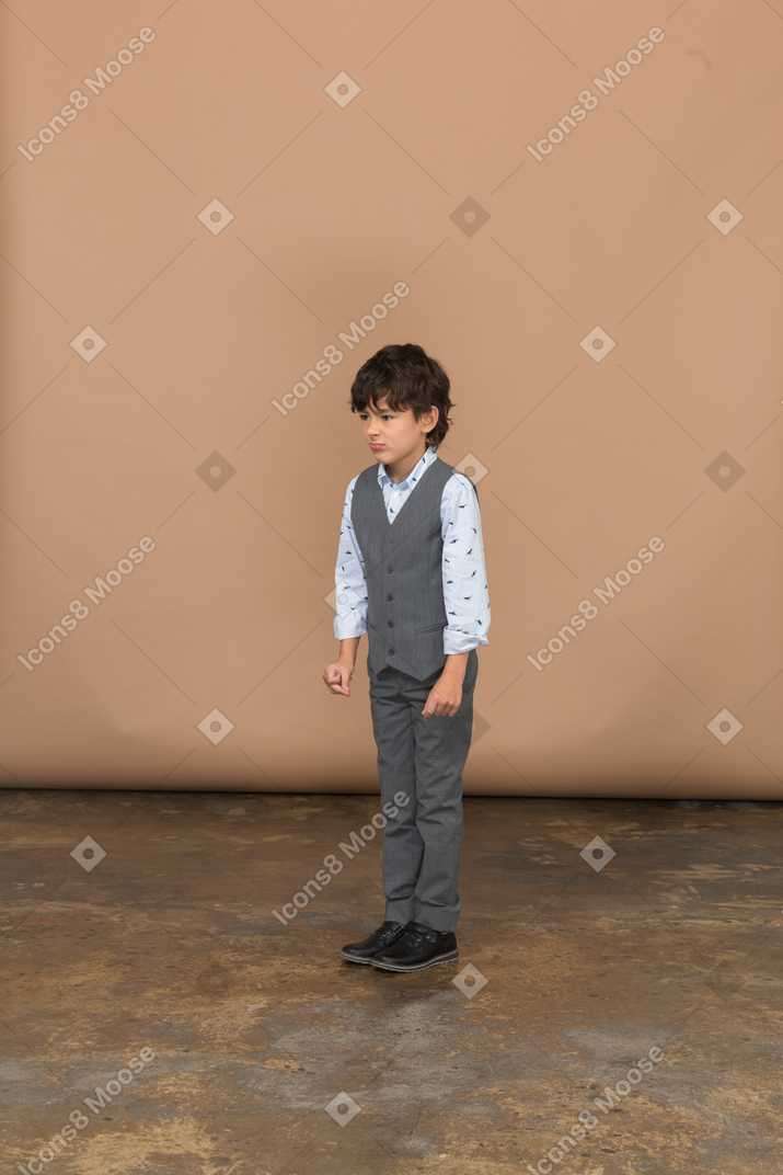 くいしばられた握りこぶしで立っているスーツを着た少年の正面図