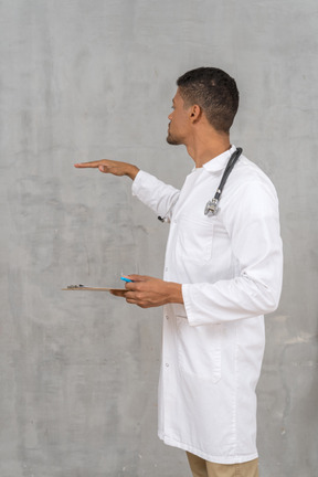 Vista lateral do jovem médico mostrando a altura de algo