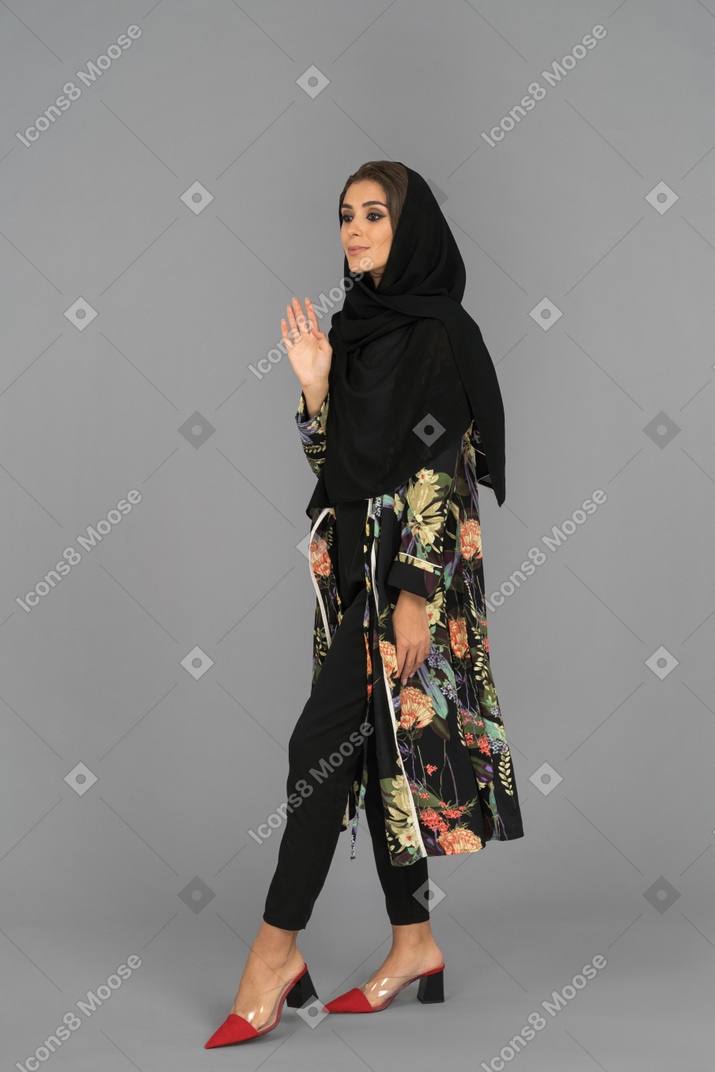 Covered muslim woman walking and waving with a hand