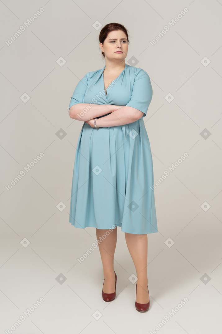 Front view of a woman in blue dress posing with crossed arms
