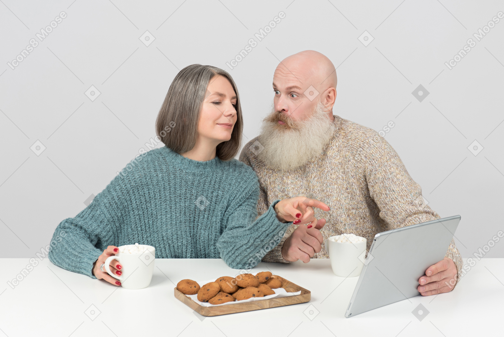 Aged couple having coffee and watching something at tablet