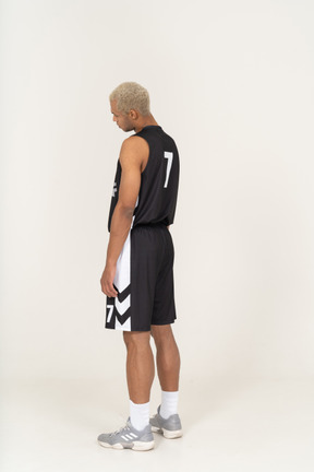 Three-quarter back view of a tired young male basketball player tilting head