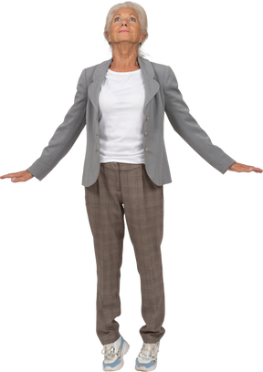Front view of an old lady in suit standing on toes and outstretching arms