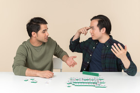 Amigos interraciais sentado à mesa e jogando scramble