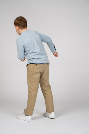 Young boy in blue shirt and khaki pants moving to the left