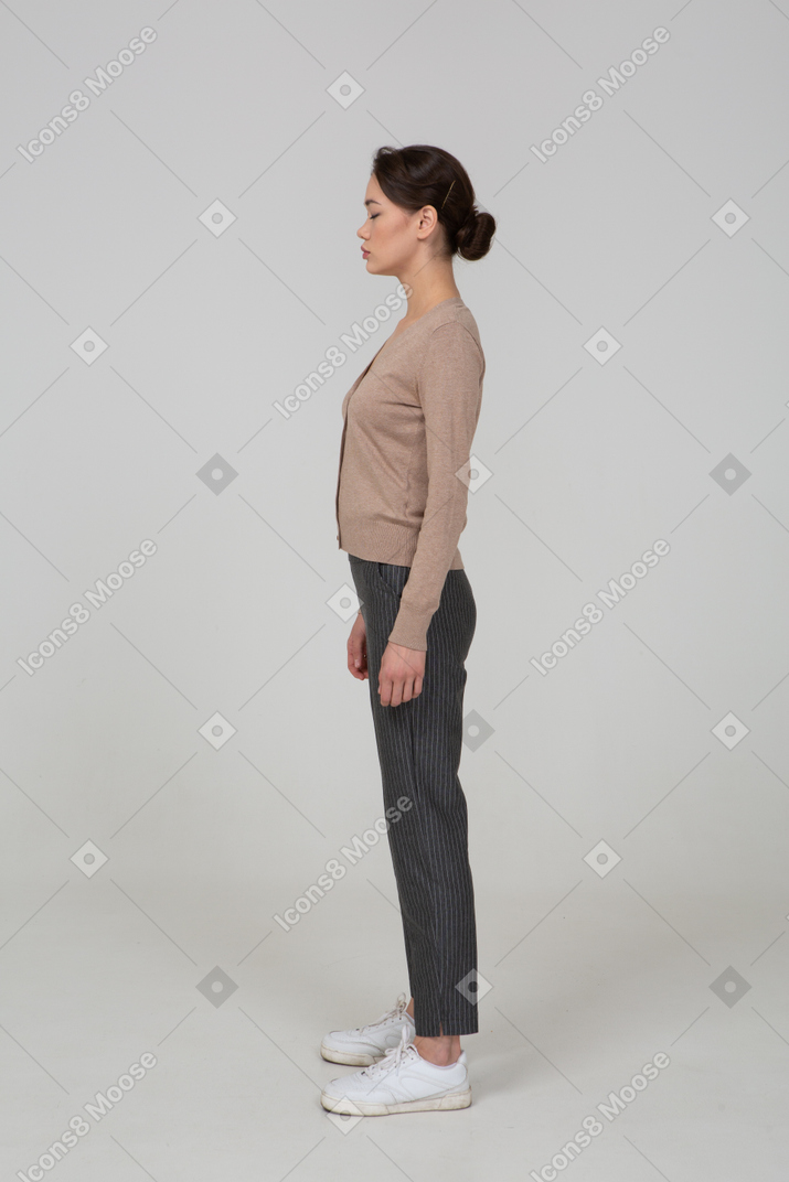 一位年轻的女士，闭着眼睛站在套头衫和裤子的侧视图