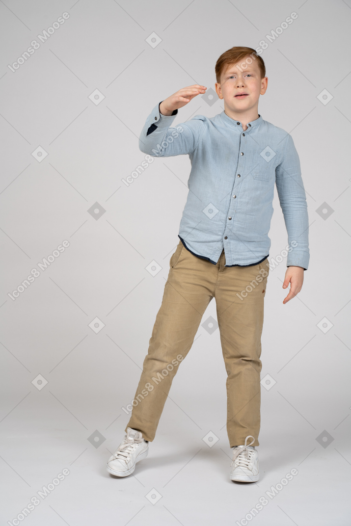 Redhead boy in blue shirt and khaki pants reaching forward