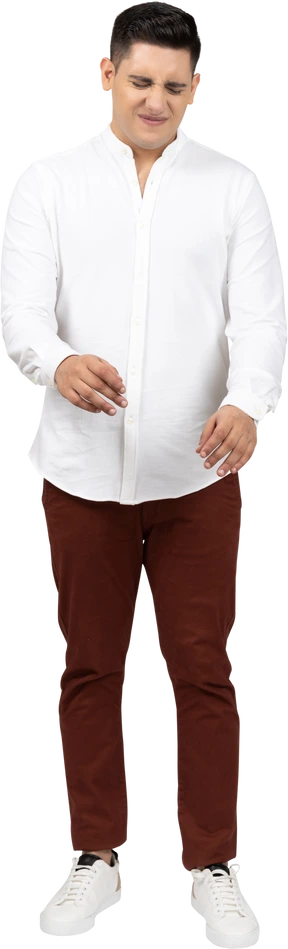 Front view of a young latino man raising hands slightly and wrinkling his face in distaste