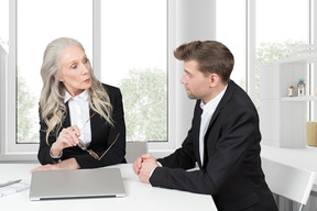 A businessman and a businesswoman talking at work