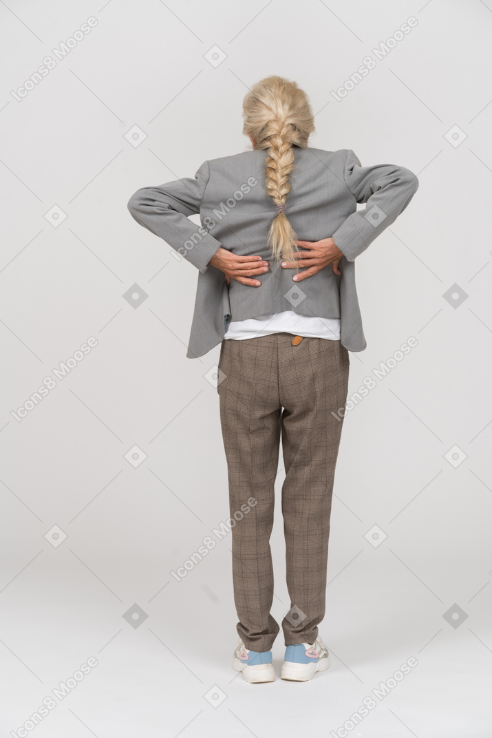 Rear view of an old lady in suit suffering from pain in back