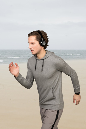 A man running on the beach with headphones on