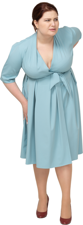 Vista frontale di una donna in abito blu che soffre di dolore nella parte bassa della schiena