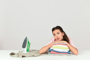 Attractive young woman looking tired of ironing